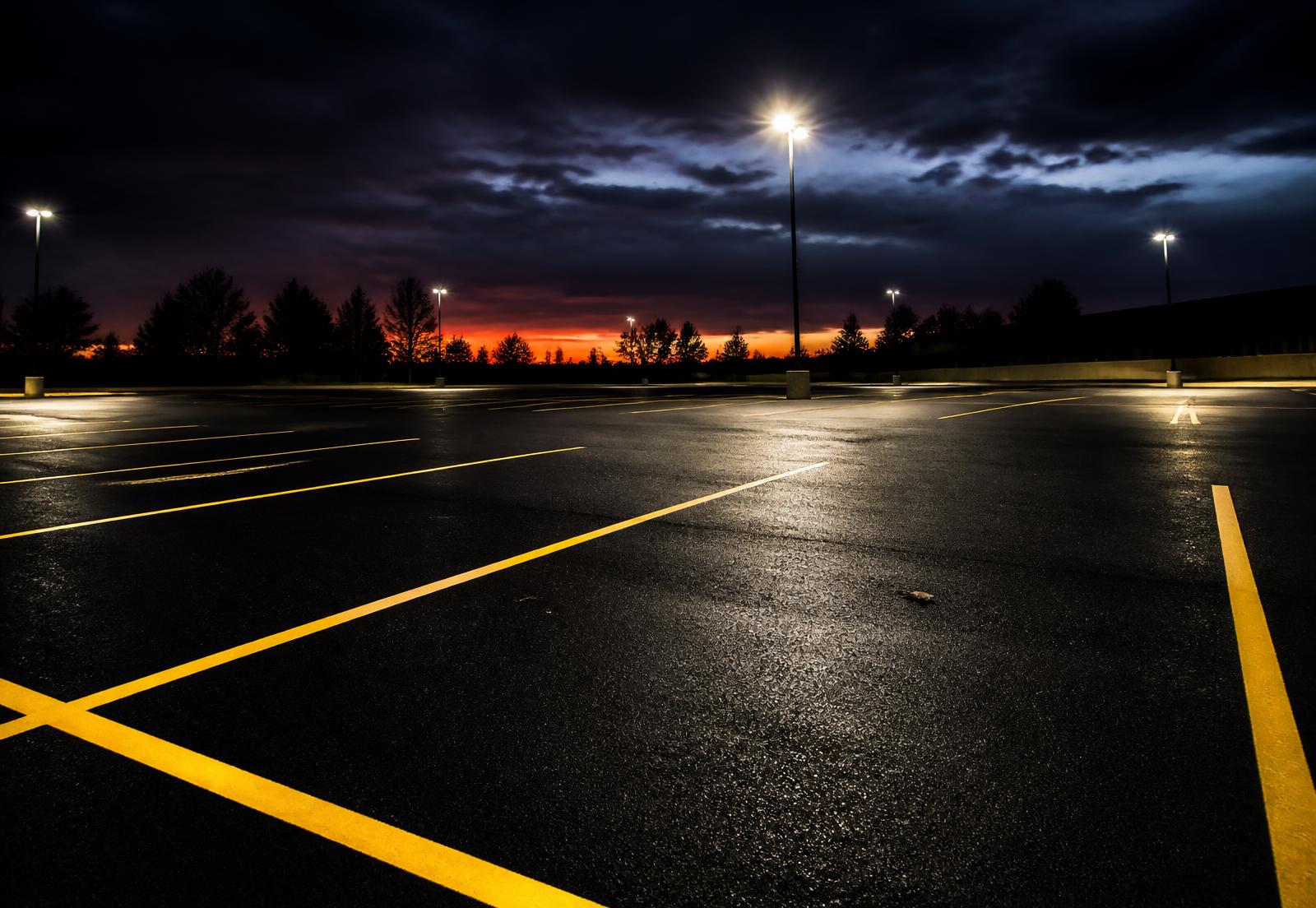 Freshly paved parking lot with bright yellow stall lines at dusk